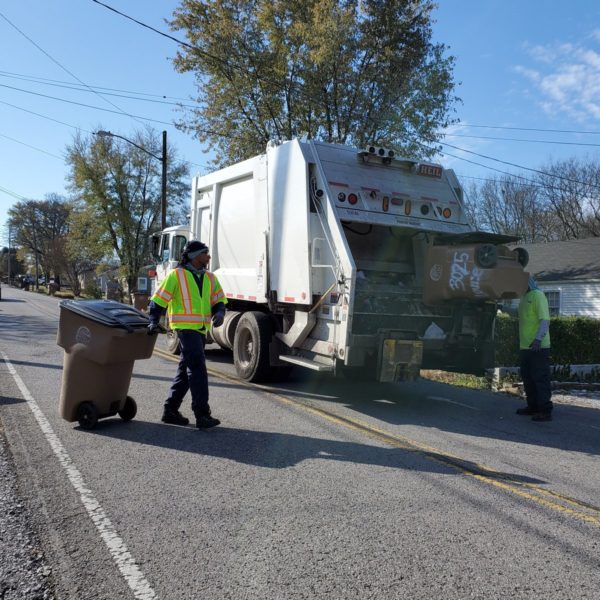 Sanitation workers load trash into a garbage truck in Nashville.