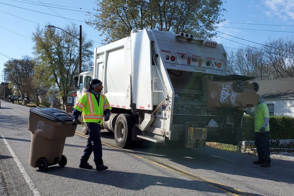 Sanitation workers load trash into a garbage truck in Nashville.