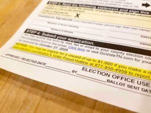 An absentee ballot application includes information about a $1,000 reward for reporting voter fraud.