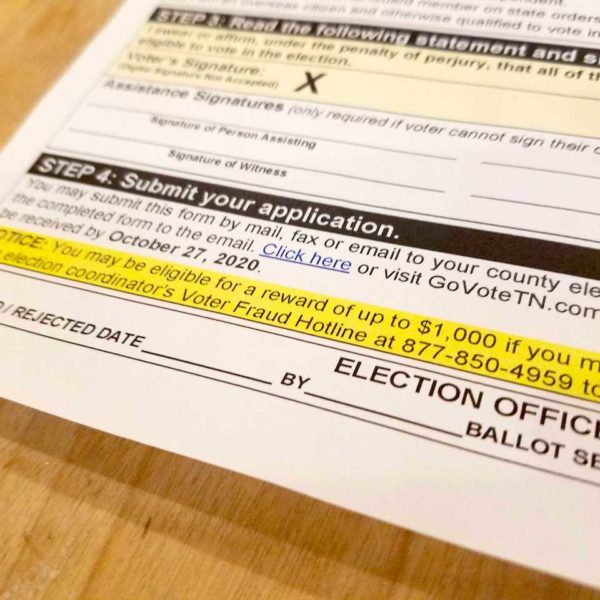 An absentee ballot application includes information about a $1,000 reward for reporting voter fraud.