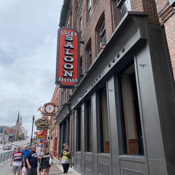 A group of people walks past a bar in downtown Nashville.