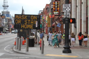 A sign on Lower Broadway tells visitors to wear a mask or stay home.