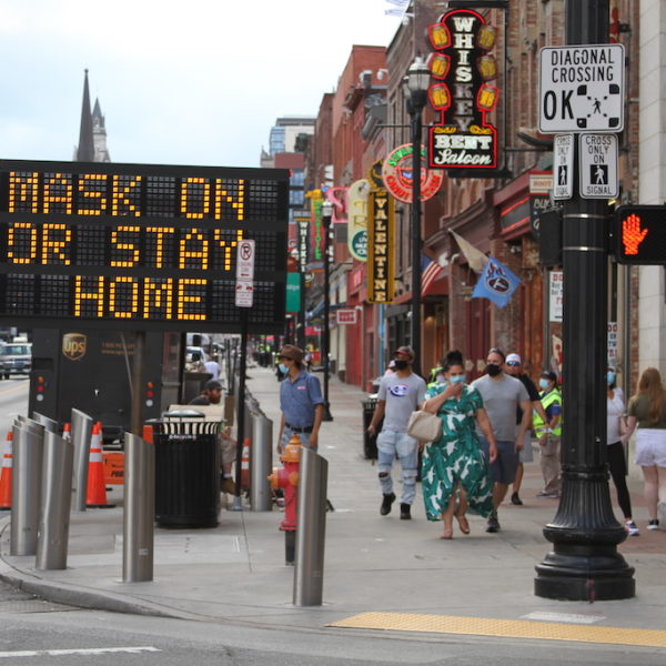 A sign on Lower Broadway tells visitors to wear a mask or stay home.