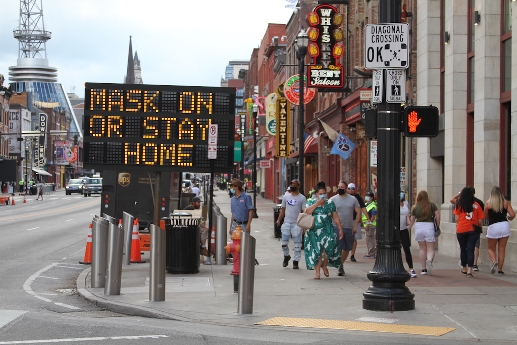 A sign on Lower Broadway tells visitors to wear a mask or stay home.