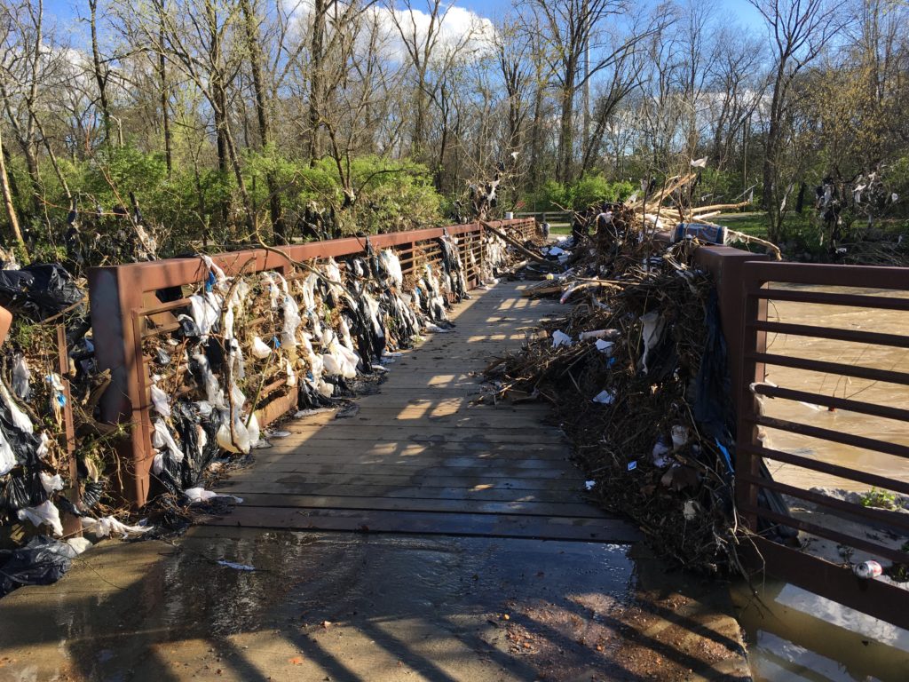 A bridge over Mill Creek is littered with shopping bags and other plastic waste.