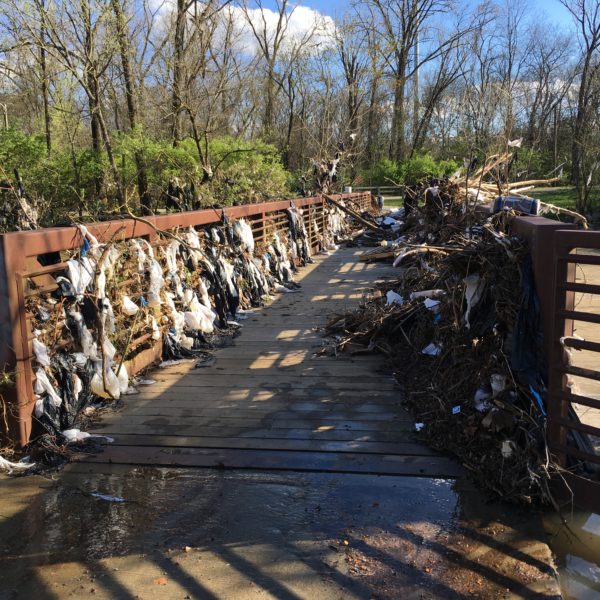 A bridge over Mill Creek is littered with shopping bags and other plastic waste.