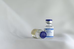 bottle containing COVID-19 vaccine on a white backdrop