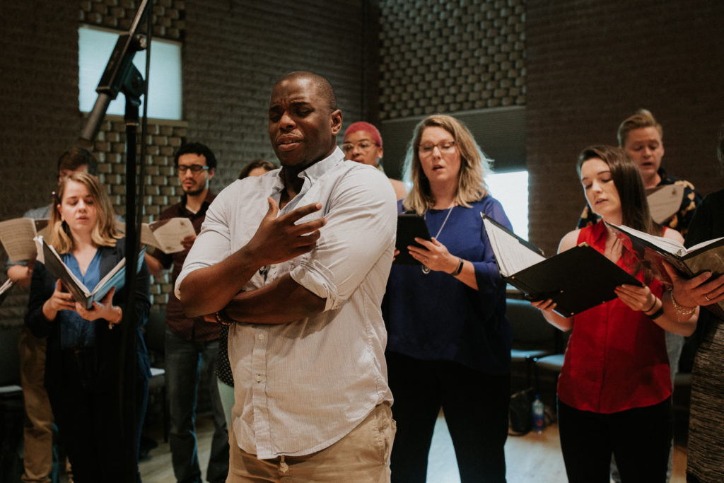 Patrick Dailey sings with emotion at the front of a choral group