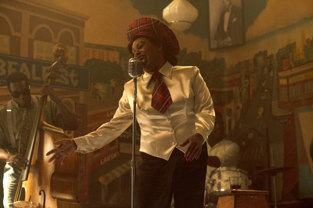 Shonka Dukureh in costume as Big Mama Thornton, singing in front of a vintage microphone