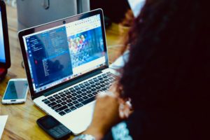 A women with curly hair writes code on a laptop.