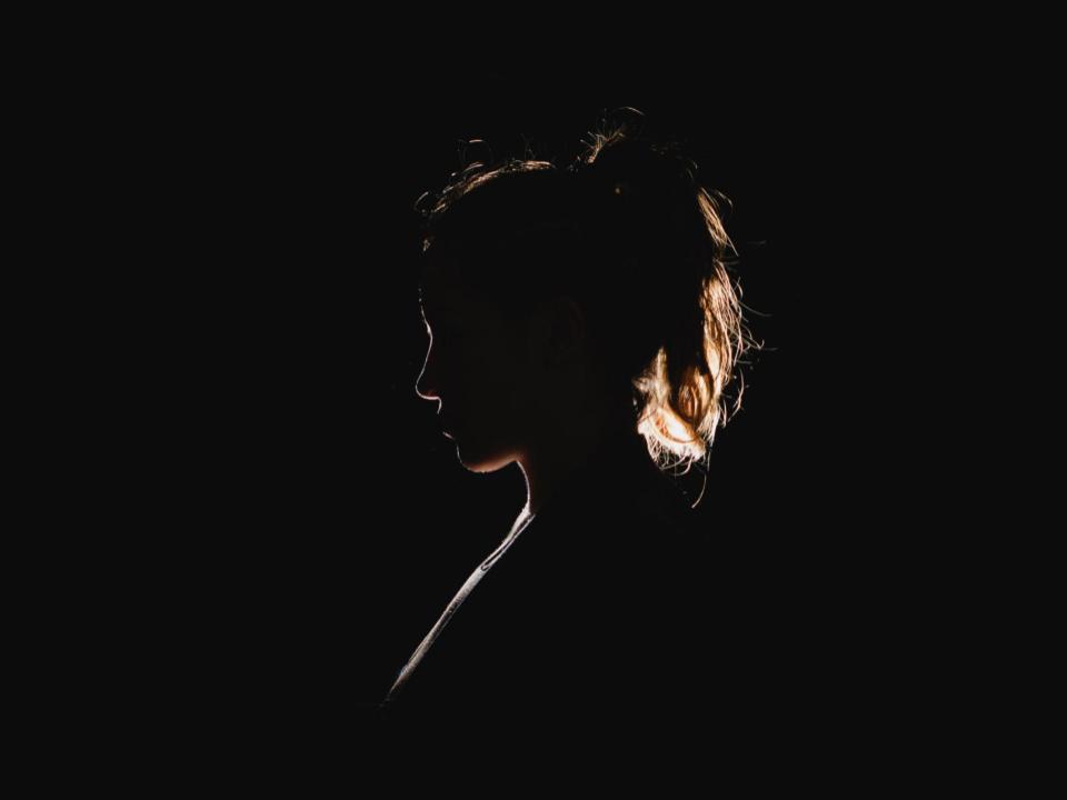 A silhouette of a woman, shown in profile against a black background