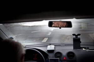 Man rubs his eyes in frustration while he's behind the driver's seat of a car.