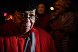 Georgia Harris, an elderly African American woman with a red coat, glasses, and a black hat