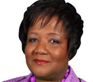 A portrait of Paulette Coleman, a middle-aged woman wearing a purple necklace and purple jacket.