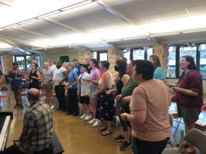 A 30-member choir rehearses in a fluorescent-lit church room festooned with pride flags.