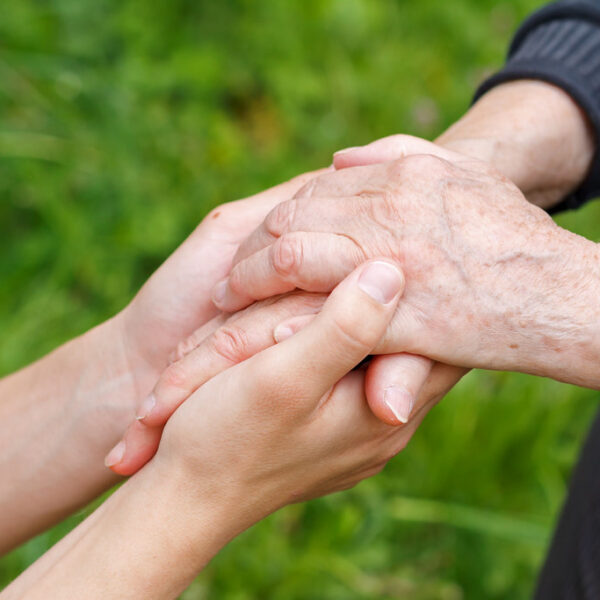 A young person's hands holding an older adult's hands