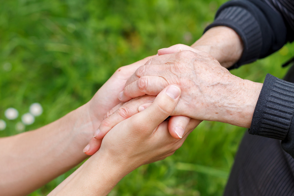 A young person's hands holding an older adult's hands