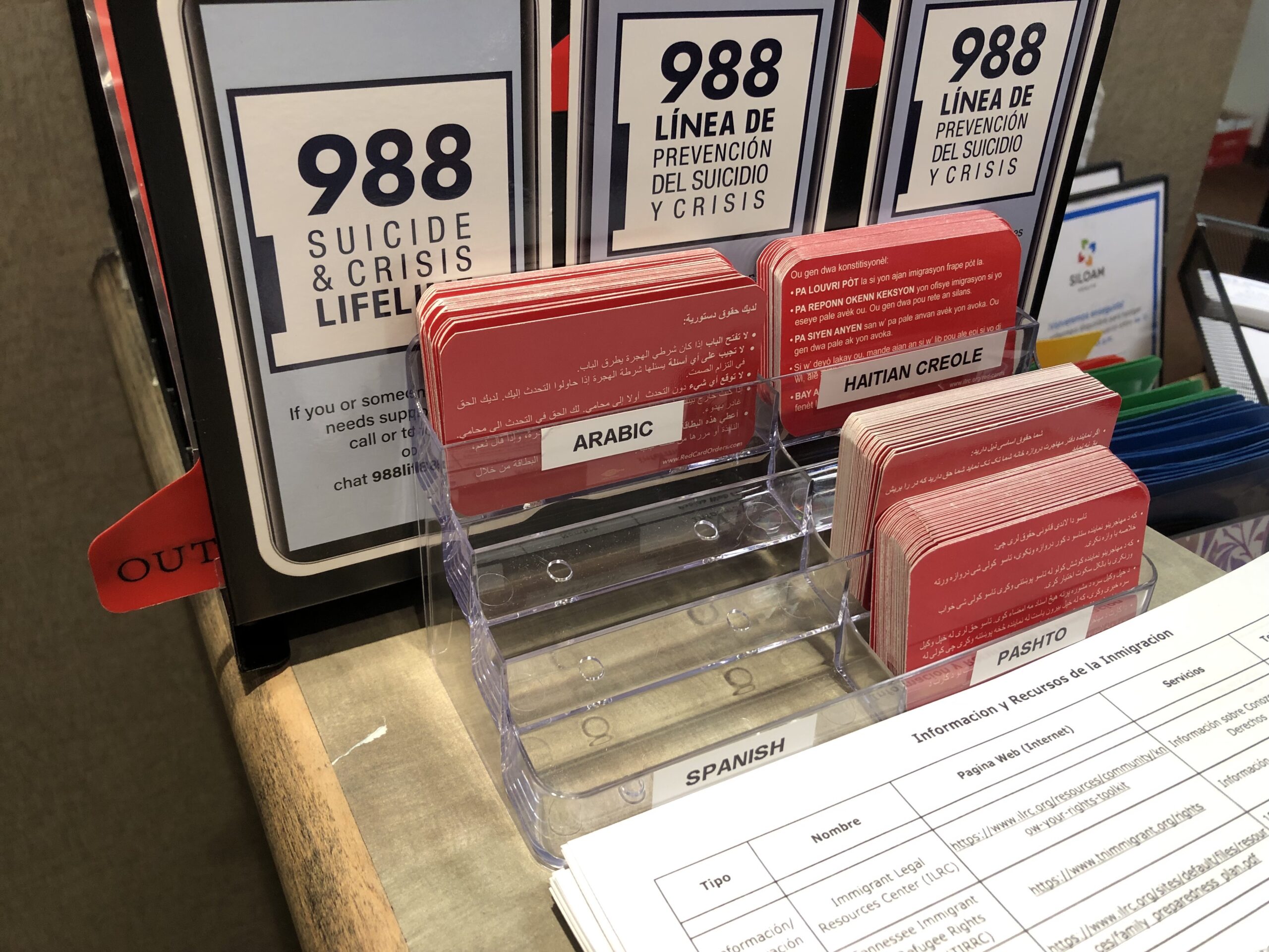 A clear plastic box with red business cards. Labels show each language the cards are written in.