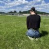 A woman kneels in the grass outside of Riverbend Maximum Security Institution.