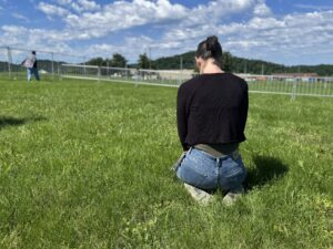 A woman kneels in the grass outside of Riverbend Maximum Security Institution.