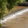 Water rushes over the top of a low-head dam.