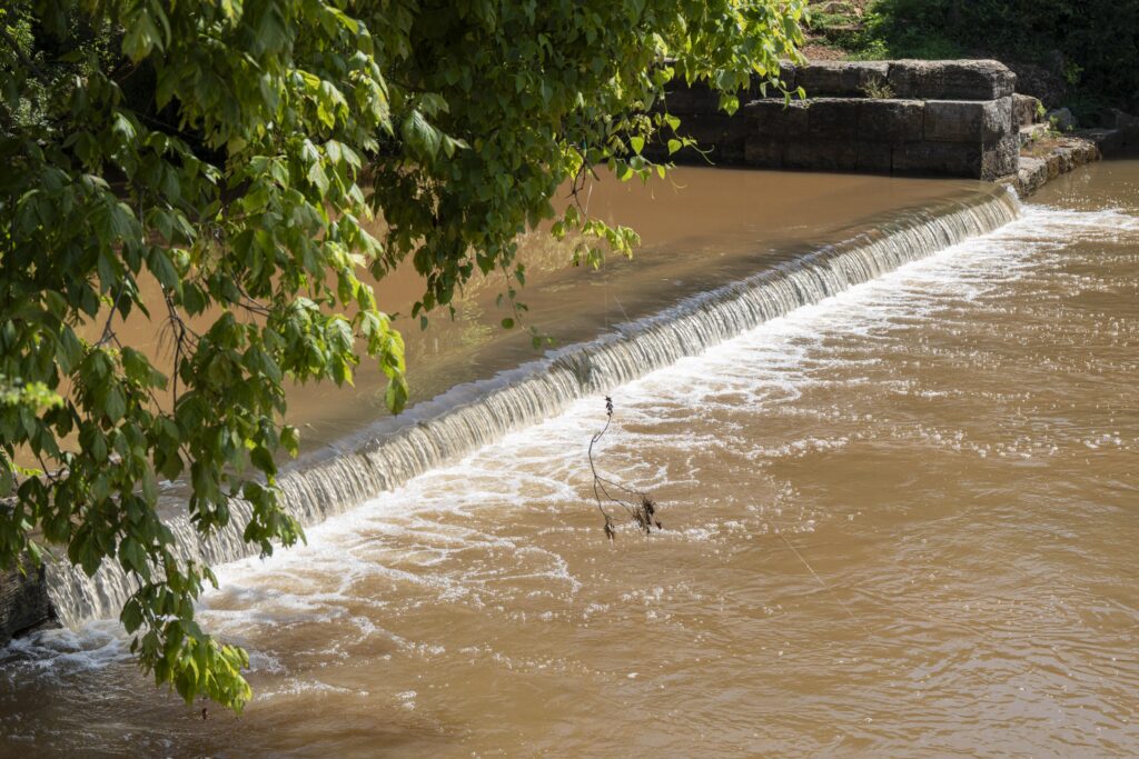 Water rushes over the top of a low-head dam.