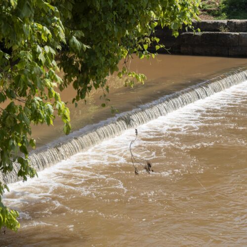 Water rushes over the top of a low-head dam.