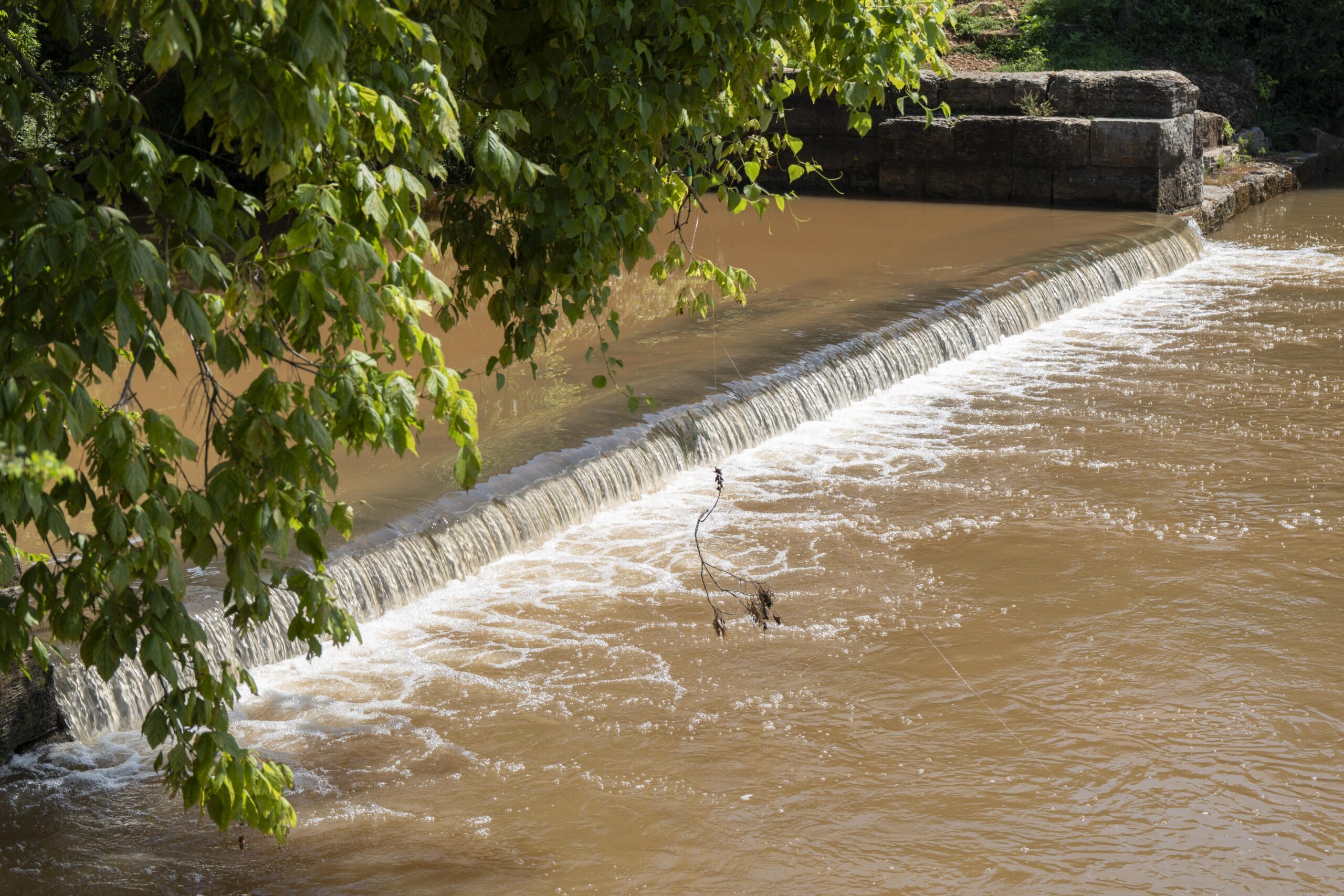 Water rushes over the top of a low-head dam.