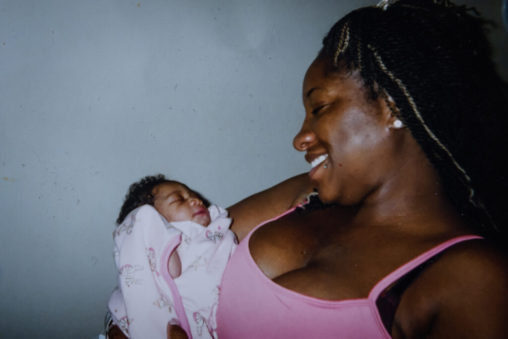 A woman smiles as she looks down at the baby she is holding.