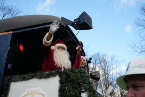 Santa Claus waves to the crowd from aboard a train.