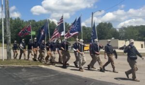 Masked members of the white nationalist organization Patriot Front march down Munfordville's Main Street on May 9th to the town's old city hall, carrying flags associated with far-right and libertarian ideologies.