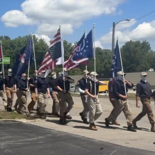 Masked members of the white nationalist organization Patriot Front march down Munfordville's Main Street on May 9th to the town's old city hall, carrying flags associated with far-right and libertarian ideologies.