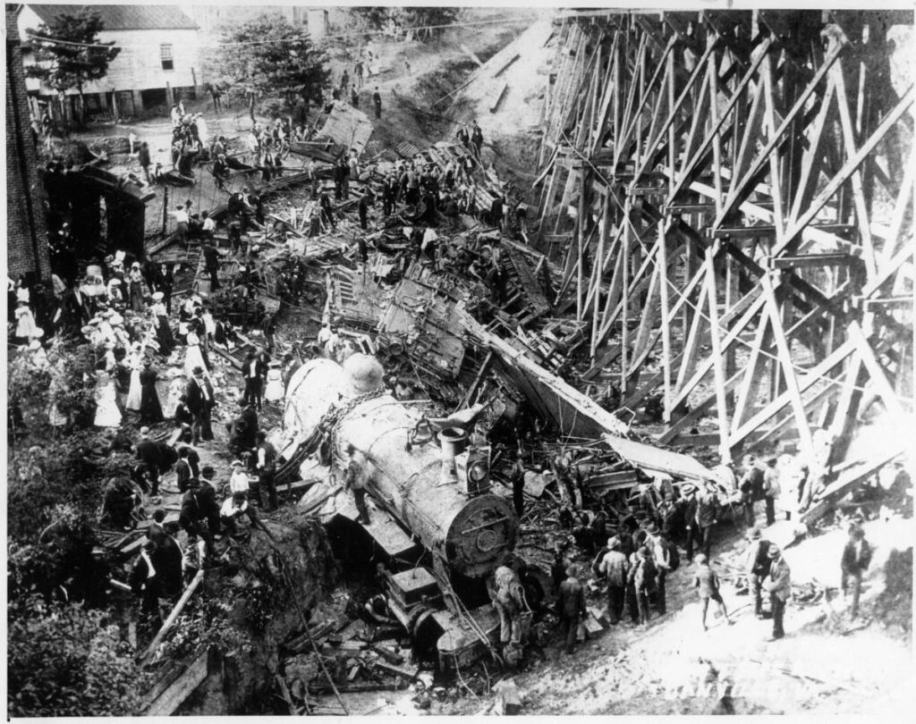People gather around a train that has jumped off the railway tracks