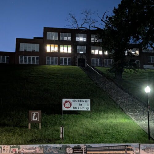 A building is seen sitting on a hilltop with a flight of stairs leading up to it.