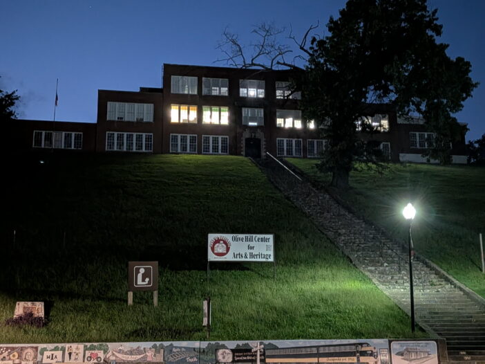 A building is seen sitting on a hilltop with a flight of stairs leading up to it.