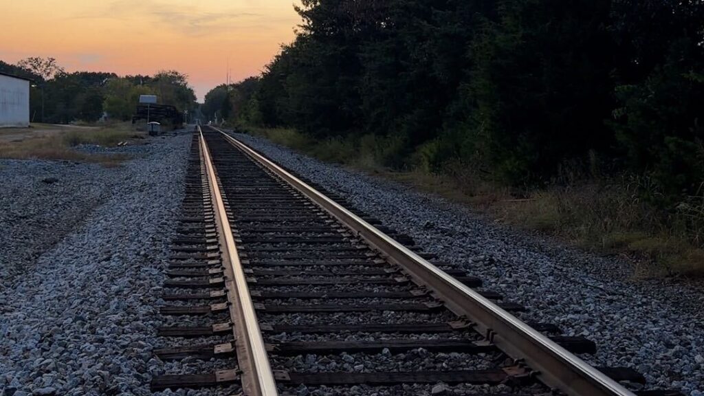 A railroad track with a sunset in the distance.