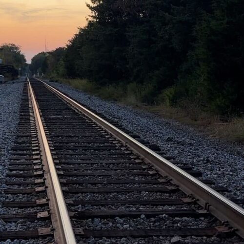 A railroad track with a sunset in the distance.