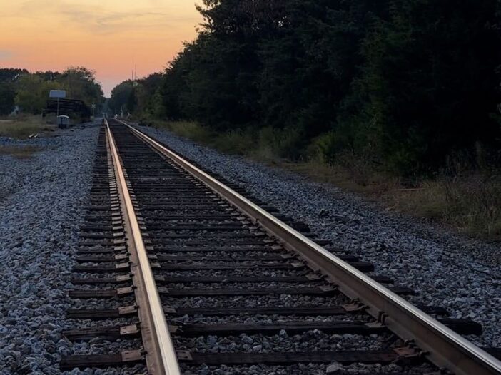 A railroad track with a sunset in the distance.