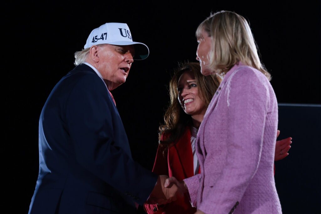 North Carolina Republican Congressional candidates, state Rep. Jennifer Balkcom and Laurie Buckhout (right), are embraced by President Trump during an election rally on Oct. 20, 2026, in Greenville, N.C.  Buckhout is running in North Carolina's 1st District, which was redrawn to heavily favor Republicans and is now a toss-up.