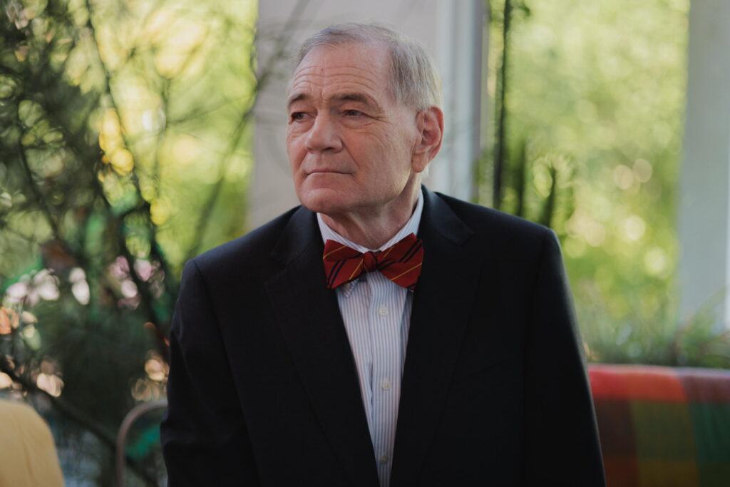 Retired Judge David Duncan poses for a photo while seated at his home in Phoenix. He is wearing a dark suit and a red bow tie with thin navy blue and marigold stripes.